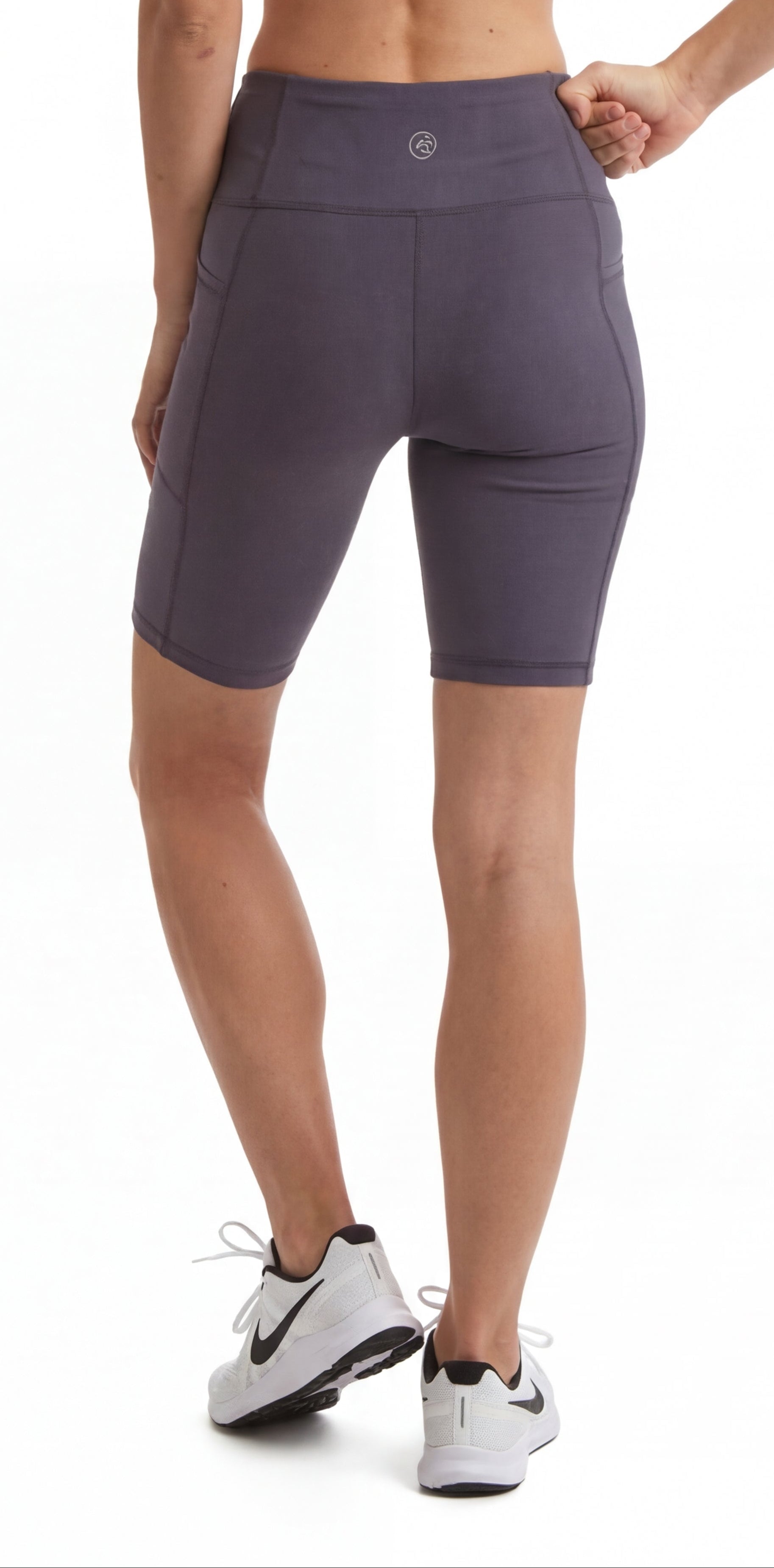 Woman wearing a black sports bra and purple shorts on a white background