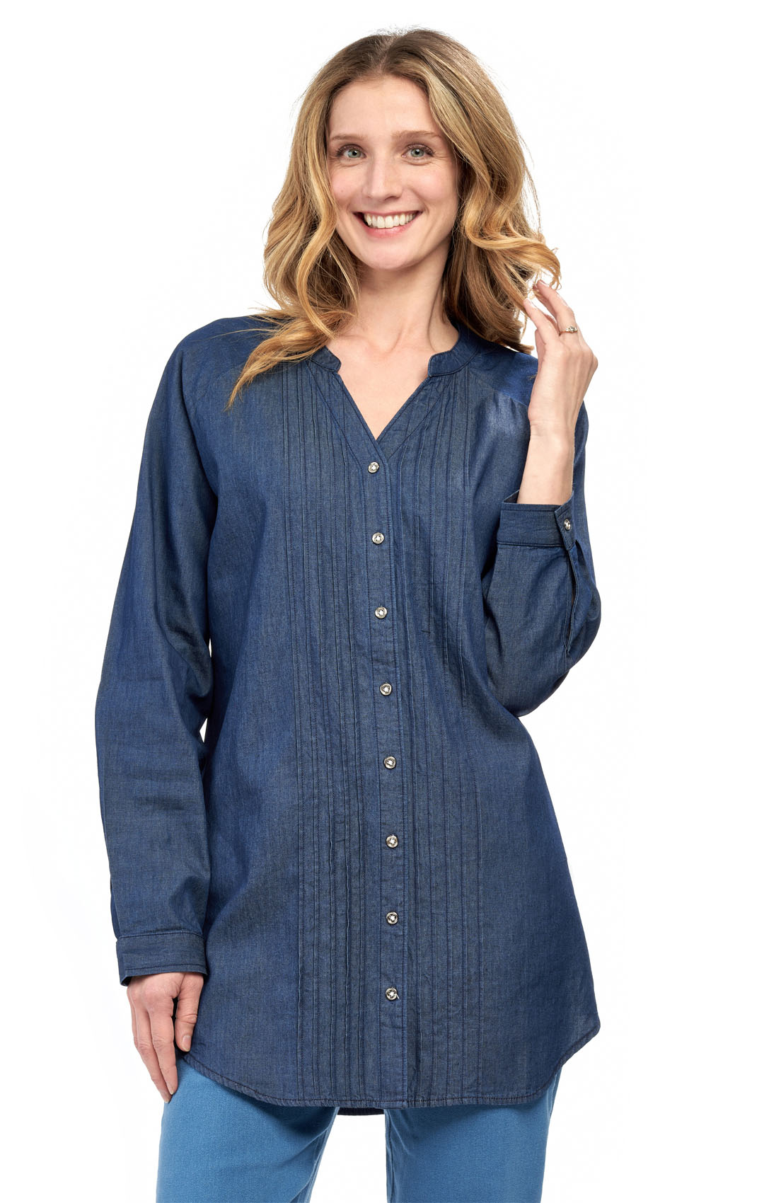 A woman wearing a blue denim tunic top with pintuck detailing and a button front, paired with jeans.